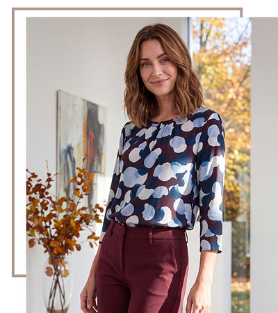 Dunkelhaarige Frau mit blau-dunkelrot gemustertem Shirt