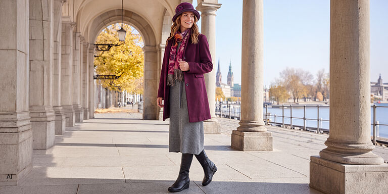 Blonde Frau in grauem Kleid und violetten Mantel und Hut